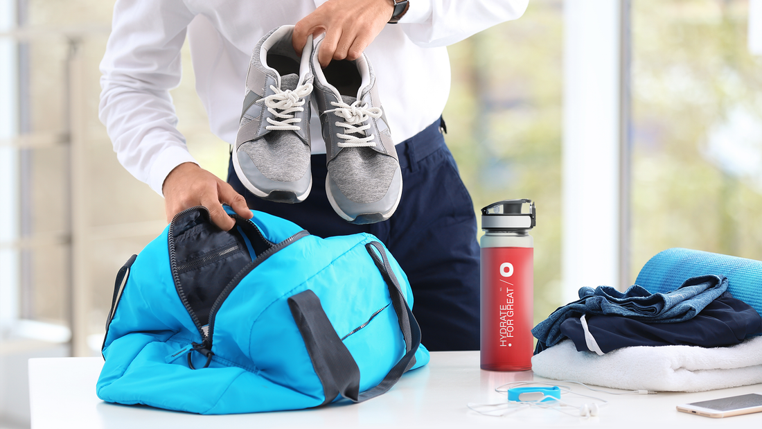 Mężczyzna pakujący buty sportowe do torby, obok stoi bidon