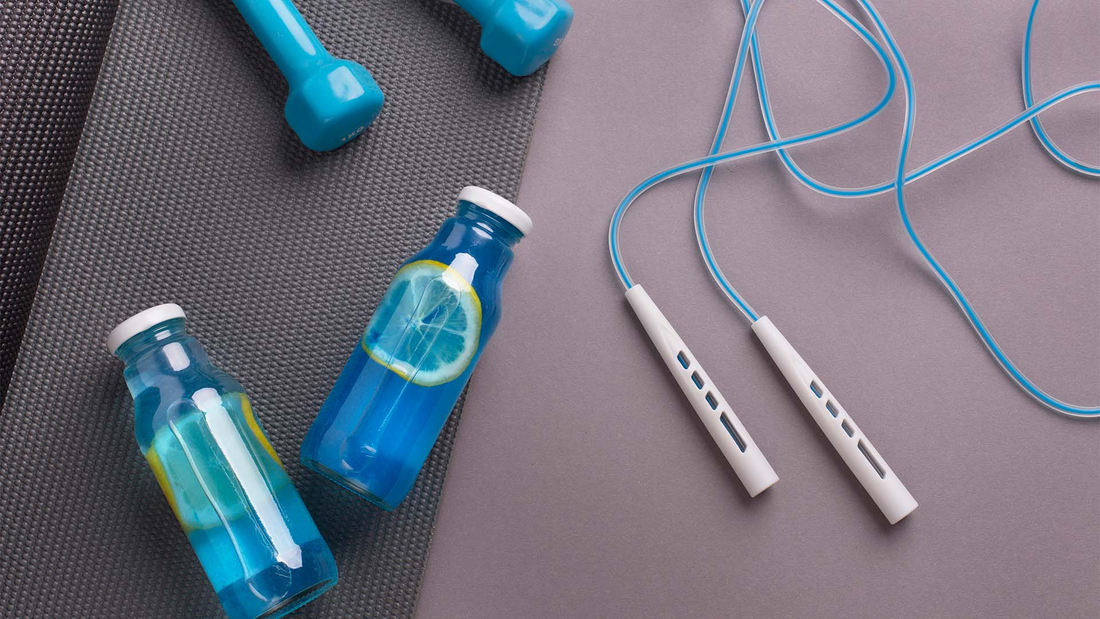 Butelki wypełnione napojem leżące przy urządzeniach z siłowni