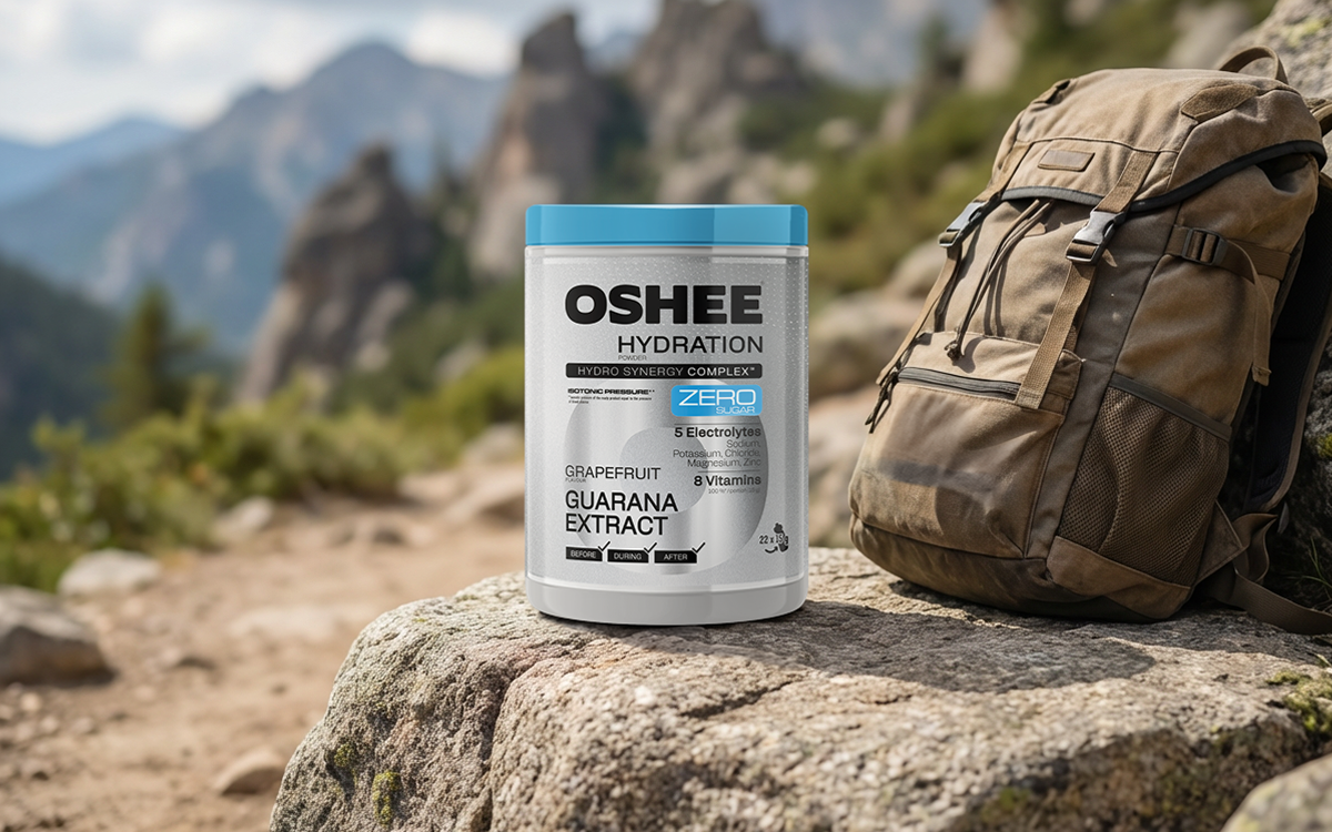 oshee grepfrut guarana zero na tle gór, obok leży plecak